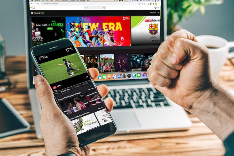 Man watching football play online broadcast on his laptop, cheering for his favourite team, making bets at bookmaker's website.